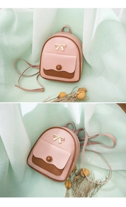 Detail of pink and brown mini backpack featuring a gold bow accent and flap pocket