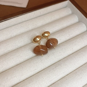 Detailed close-up of vintage resin amber earrings with gold metal studs on velvet