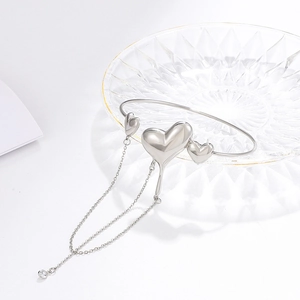 Silver molten heart bracelet with long chain tassels on elegant glass texture tray