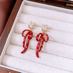 Macro detail of vintage red bow earrings with gold plating and square zircon stone