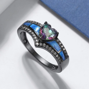 Detalle macro de un anillo de corazón de metal oscuro con gema morada y toques azules