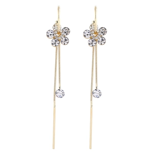 Boucles d'oreilles fleurs dorées avec pampilles et cristaux blancs sur fond blanc