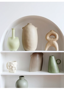 Minimalist Morandi ceramic vases and abstract sculptures displayed in an arched niche