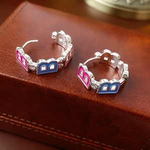 Macro detail of silver hoop earrings featuring pink and blue enamel letter B design