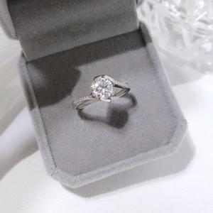 Close-up detail of a 1-carat round brilliant cut engagement ring in a gray box.