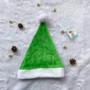 Detailansicht einer grünen Plüsch-Weihnachtsmütze mit weißem Bommel auf Teppich