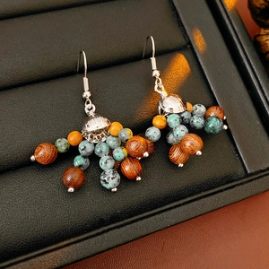 Close-up of bohemian earrings with wooden and stone beads on a black display tray