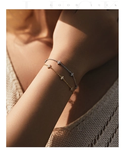 Close-up of gold and silver clover bracelets with sparkling stones on woman's wrist