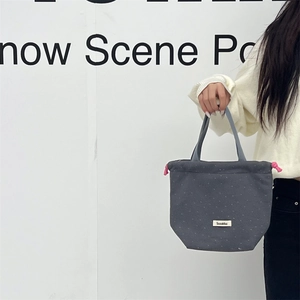 Detail of grey wool-texture tote bag with white polka dots and pink drawstring accent