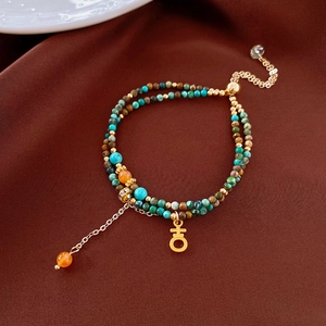 Dettaglio di un bracciale bohémien a doppio strato con perle di pietra naturale e ciondolo
