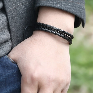 Détail d'un bracelet en cuir noir tressé multicouche porté au poignet en extérieur
