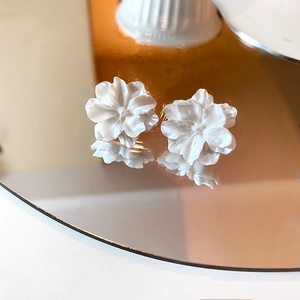 Detailansicht der 3D-Ohrstecker aus weißem Harz mit matten Blüten auf einer Spiegelreflexion