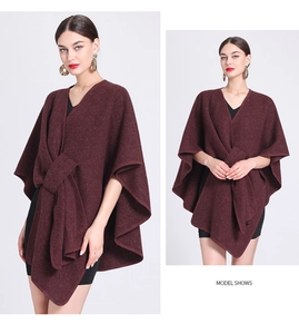 Detailed view of deep red knitted poncho with tie-knot closure and irregular hemline