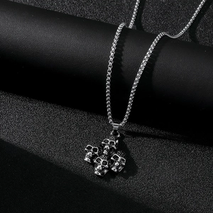 Vue détaillée du collier en acier inoxydable argenté avec pendentif à quatre crânes