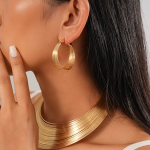 Detailed view of layered gold circular earrings and wide choker on model with metal shine