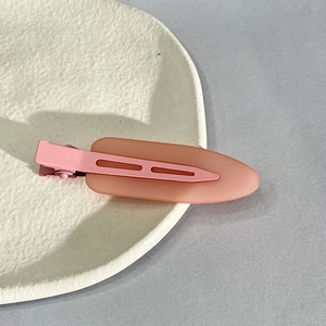 Close-up of pink matte acrylic hair clip with hollow design on a beige ceramic plate