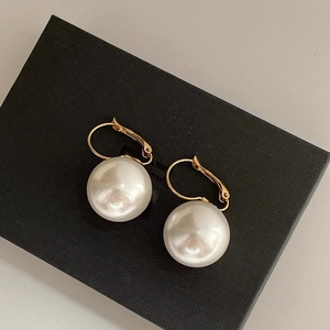 Detail of 14K gold plated earrings with large white pearls on a textured black gift box