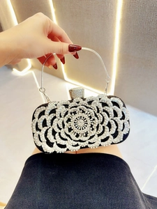 Detail of black evening clutch bag with sparkling floral rhinestone pattern and silver chain