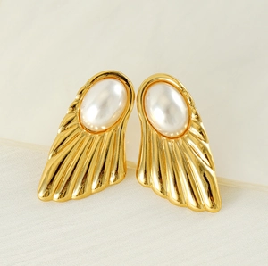Macro detail of gold fan-shaped stud earrings with white oval pearls and pleated wings
