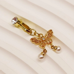 Détail d'un clip de nombril papillon doré avec strass brillants et perles blanches
