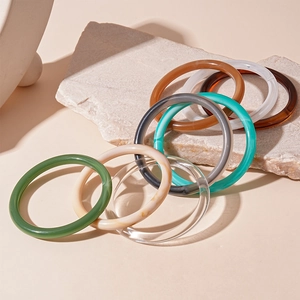 Minimalist geometric acrylic resin bangles in various colors on a stone plate