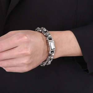 Detail of silver skull link bracelet paired with a black suit for a punk vintage style
