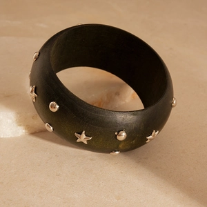 Detail view of dark green wooden bangle with silver star and round metal studs decoration