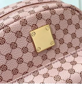 Close-up of pink textured leather bag with clover pattern and golden square hardware plate