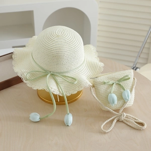 Detail of child's straw sun hat and matching bag with green ribbon and tulip pendant