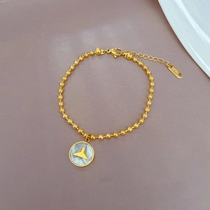 Vue macro du bracelet à billes en acier doré avec pendentif nacre en queue de sirène