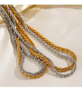 Detail of shimmering gold and silver twist rope chains on a textured fabric background