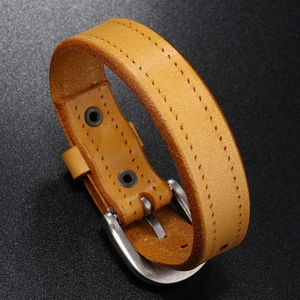 Detail of yellow leather bracelet with metal buckle and double row stitching on black texture