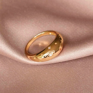 Macro shot of gold brass star and eye motif ring with cubic zirconia on pink silk