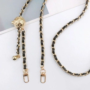 Detail of adjustable gold metal chain strap with black leather and hollow sphere buckle