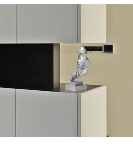 Detail of silver Silence is Golden sculpture with finger to lip gesture on modern base