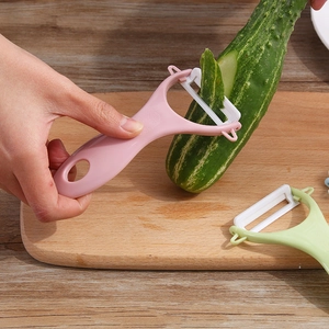 Pink ceramic peeler for kitchen peeling cucumber on a wooden board professional view