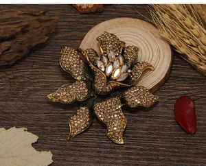 Macro shot of vintage gold flower brooch with bronze rhinestones on a rustic wood background