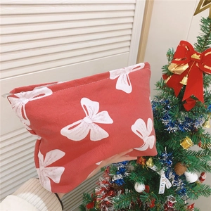 Detailed close-up of a red canvas makeup bag with white bow pattern and silver zipper