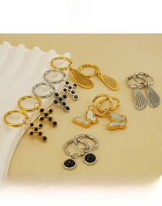 Detailed close-up of titanium steel earrings with butterfly, cross, and wing charms
