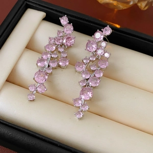 Macro shot of pink zircon fringe earrings with silver needle on beige velvet