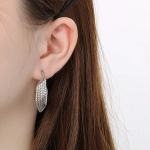Close-up of silver multilayer woven steel earrings worn to show texture and size