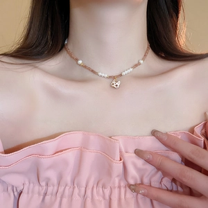 Détail du collier choker avec perles roses et un pendentif masque de lapin doré