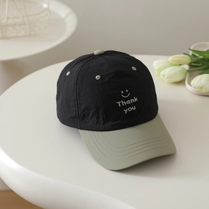 Detail of kids baseball cap featuring smiley face embroidery and breathable fabric