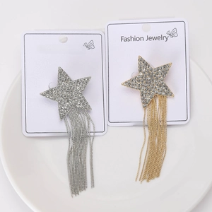Detailed view of silver and gold star tassel brooches with rhinestones on a white plate