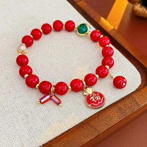 Détail du bracelet en perles rouges avec pendentif doré Fu et émail décoratif