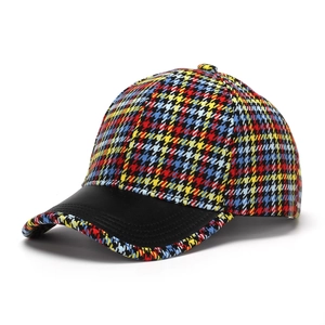 Close-up of multicolor houndstooth fabric texture and black faux leather brim on baseball cap