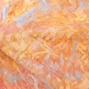 Macro view of floral lace texture in orange and gold mesh for crop top and skirt set