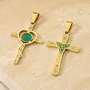 Vue détaillée de pendentifs croix en or 18 carats avec gemmes vertes et motif de serpent
