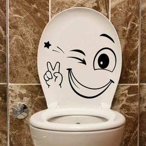 Creative wink emoji sticker on white toilet lid with marble wall background