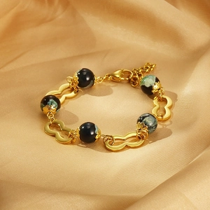 Bracelet en acier inoxydable doré avec maillons infini et perles de résine sur satin